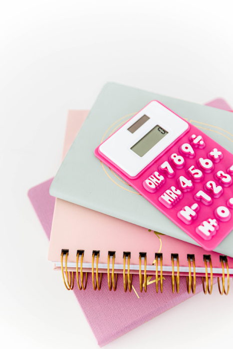A stack of pink notebooks and a calculator