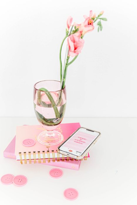 pink flowers sitting in a glass on pink books, ready for accountability groups